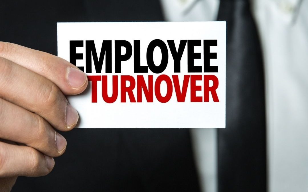 Man in a suit holding a sign that reads "Employee Turnover"