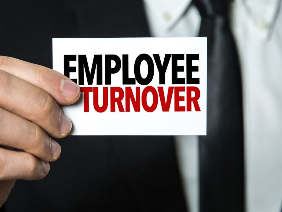 Man in a suit holding a sign that reads "Employee Turnover"