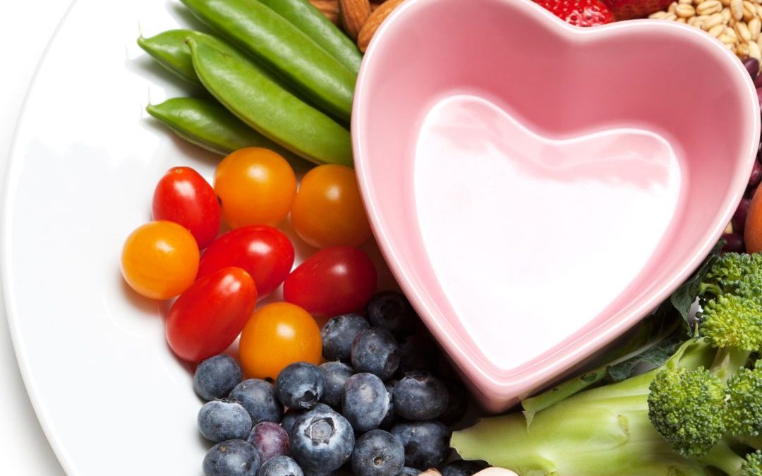 Healthy foods displayed on a white plate with a heart-shaped bowl in the centre