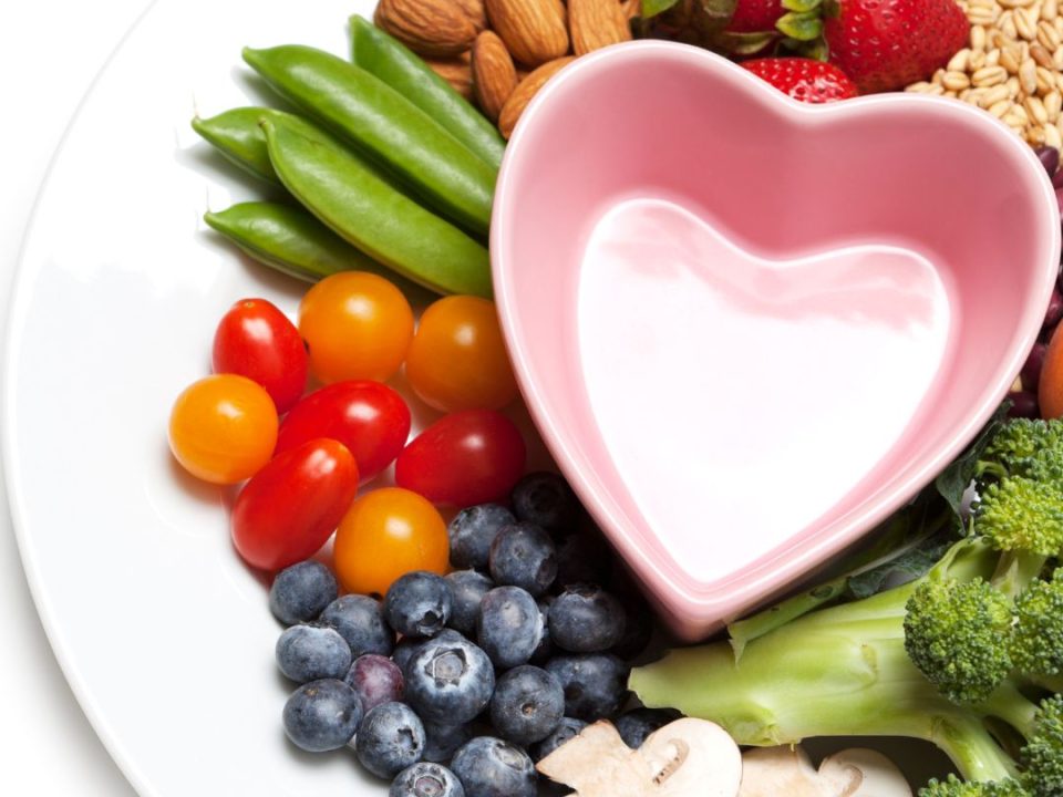 Healthy foods displayed on a white plate with a heart-shaped bowl in the centre